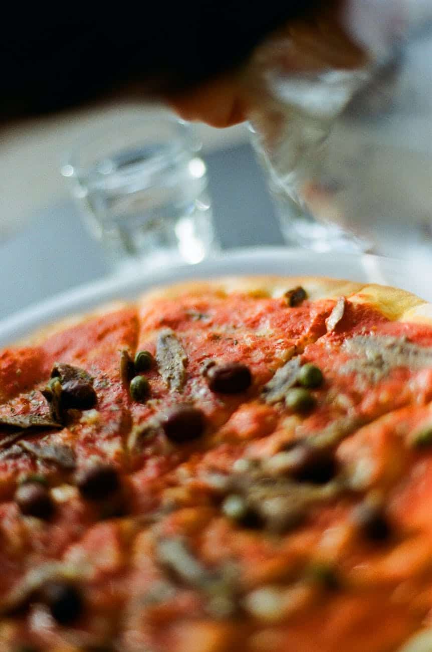 close up shot of delicious pizza with anchovies and olives